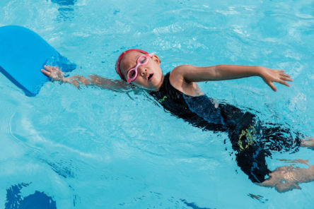 child swimming front crawl with float